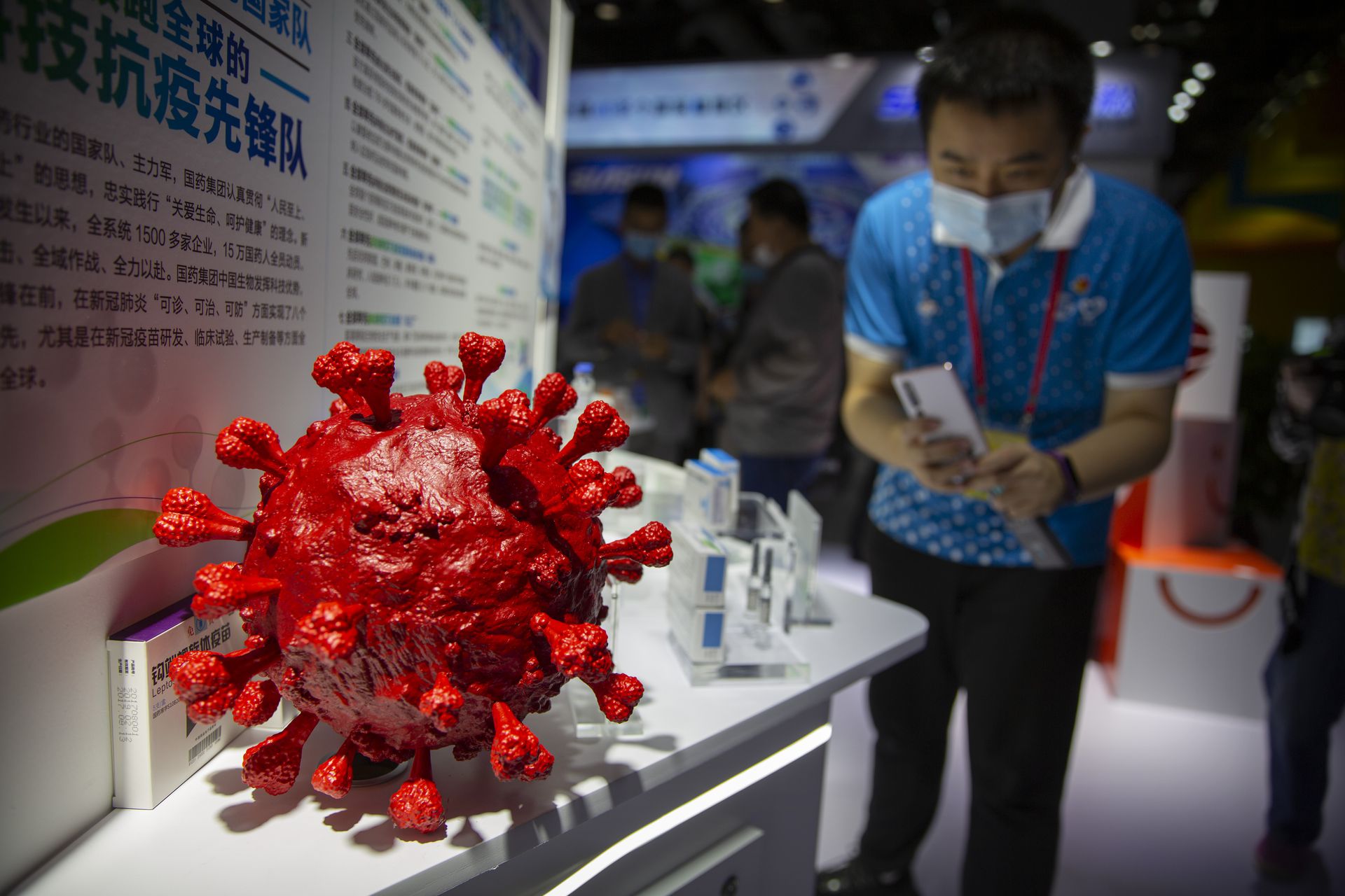 一些民众拍摄中国生物展出的两个新冠病毒灭活疫苗。（Reuters）