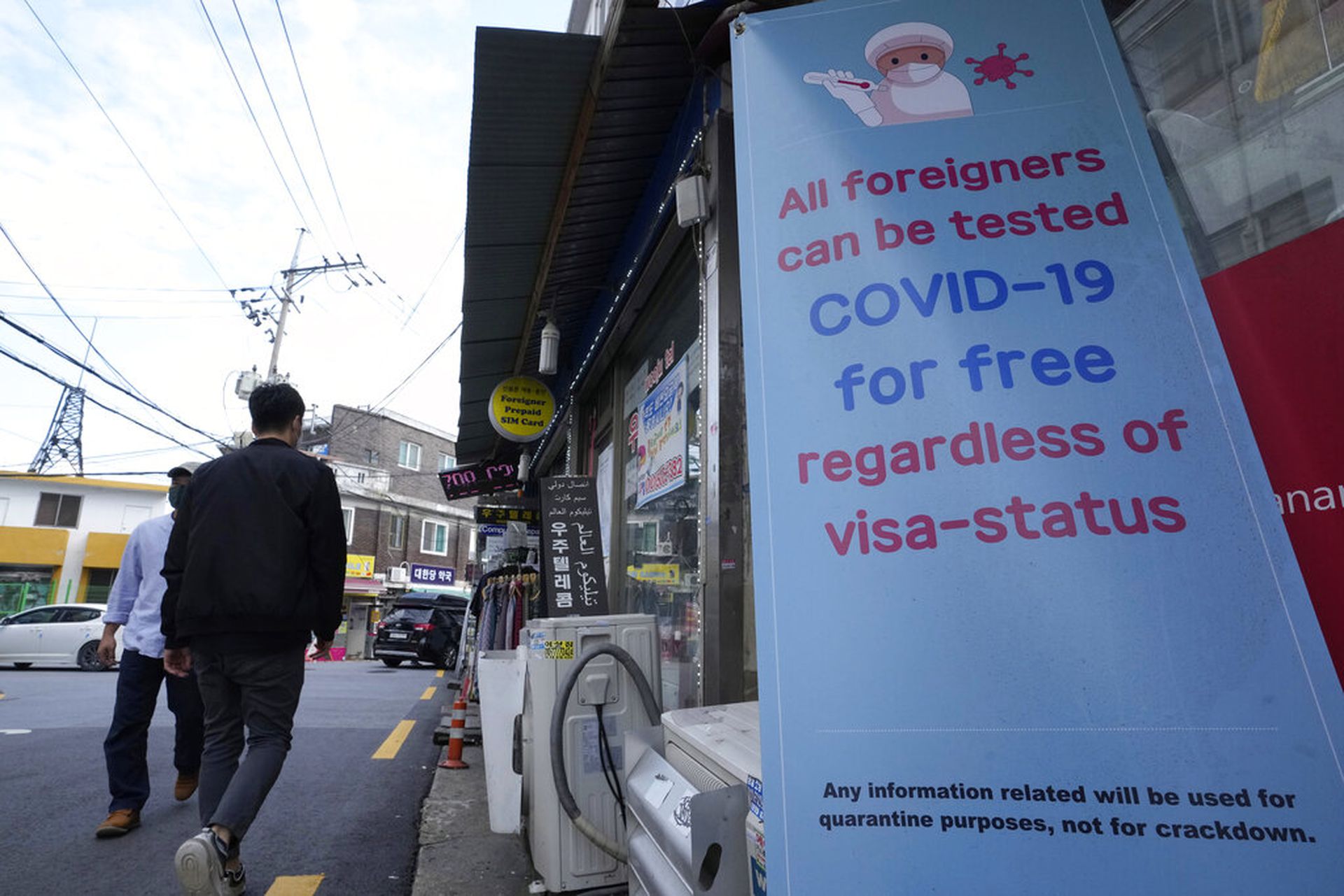 韩国新冠肺炎疫情：2021年10月15日，首尔梨泰院的途人行经一幅提供病毒检测资讯的告示。梨泰院是有名的商业区、旅游区，也是有大量外国人居住的地方。（AP）