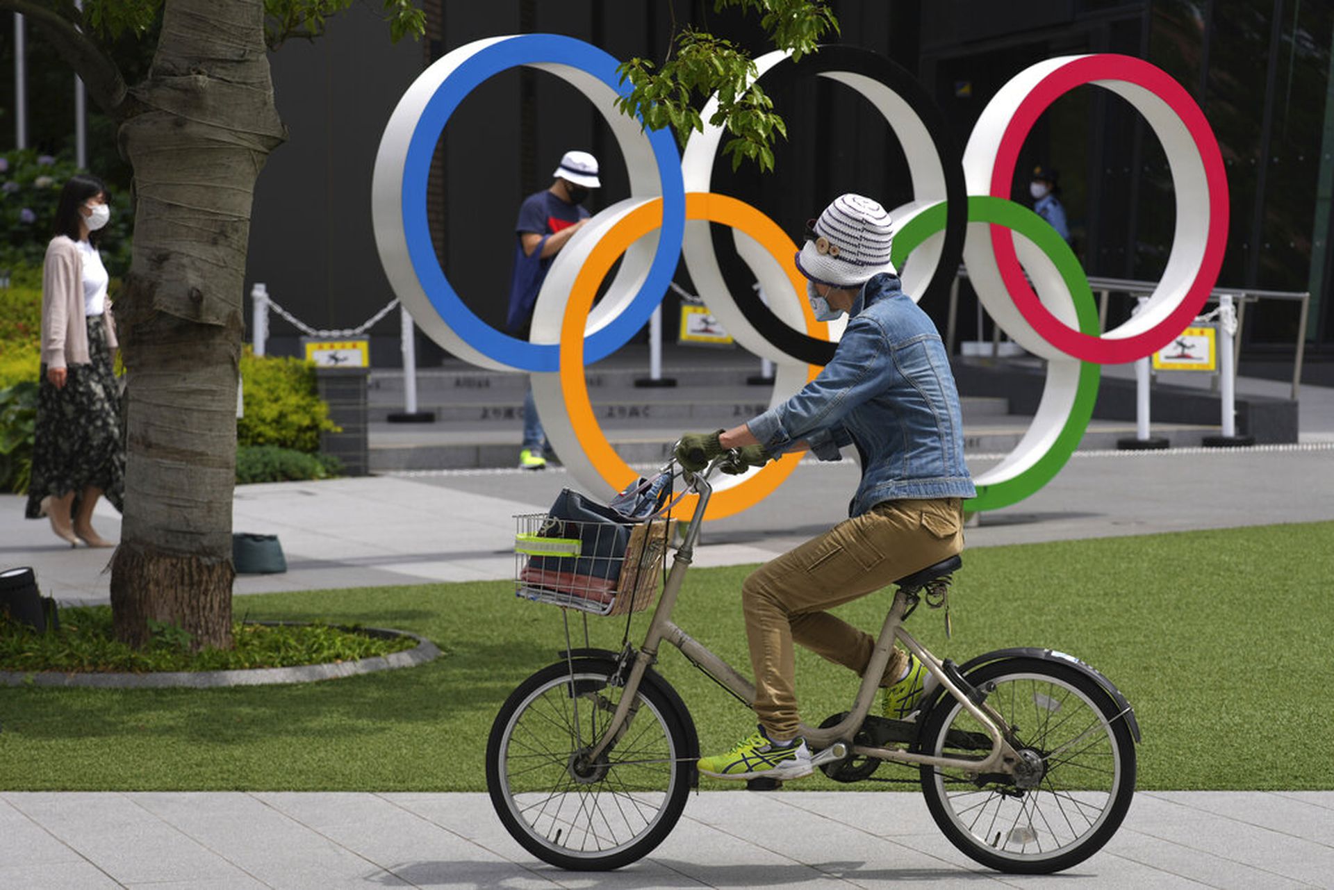 日本新冠肺炎疫情：图为6月2日，东京一名女子踏单车经过奥运五环标志户外装置前方。（AP）