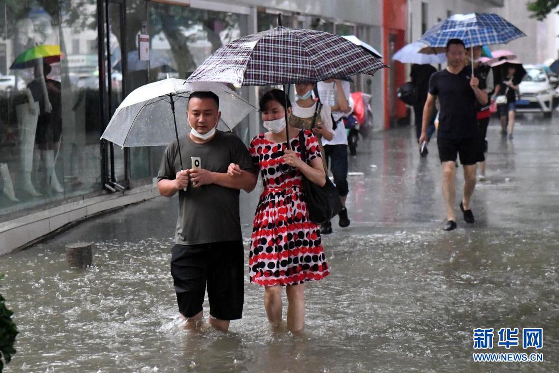7月20日，郑州市民涉水前行。（新华社）